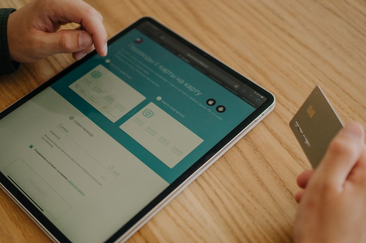 gallery-2 Hands making an online purchase using a tablet and credit card on a wooden table.