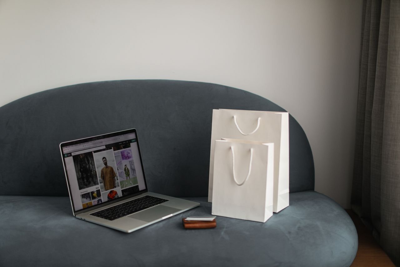 services-02 Online shopping setup with a laptop and shopping bags on a stylish couch.